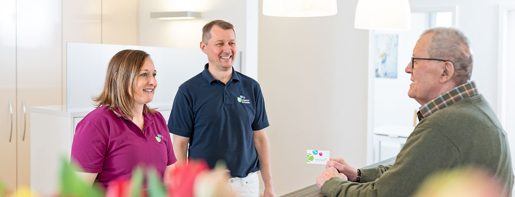 Unser Empfangsbereich mit unseren zwei Zahnärzten und einem Patienten.