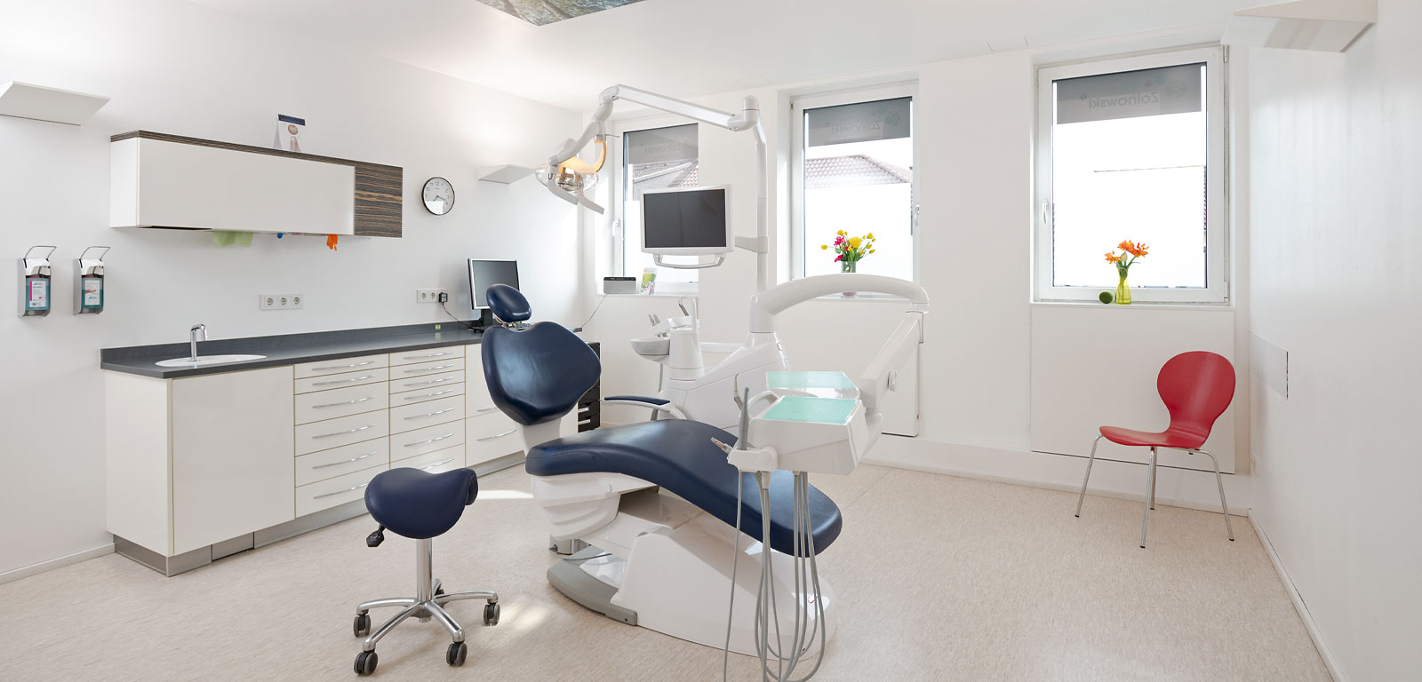 Unser Behandlungszimmer. Ohne Patienten. Behandlungsstuhl im Vordergrund. 